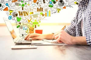 Creative entrepreneur brainstorming with laptop, notebook, and colorful business icons representing ideas and strategy