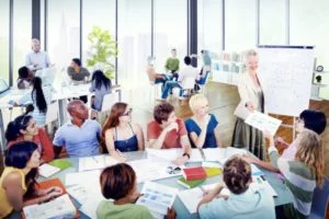 Corporate training session with instructor presenting on flip chart to diverse group of adult learners in modern classroom