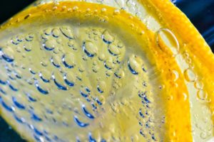 Close-up of lemon slices in sparkling water with bubbles, symbolizing freshness and citrus flavor.