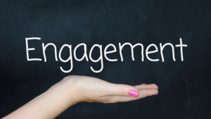 Hand holding the word "Engagement" written in white on a blackboard background