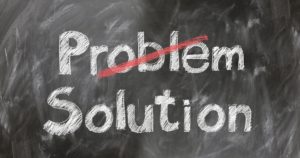 Chalkboard with the words 'Problem' crossed out in red and 'Solution' written below in white chalk