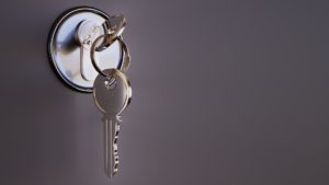 Silver key hanging on a modern key holder attached to a wall