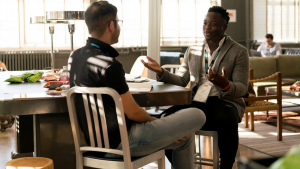 Two men having a conversation at a casual meeting table in bright office space