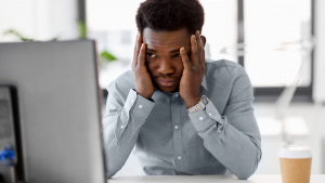 Frustrated man holding his head in an office environment