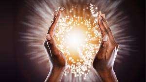 Two hands framing a glowing orb of light with sparkling particles, symbolizing energy, magic, or healing