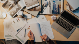 Person reviewing screenplay script with papers and laptop on desk