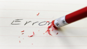 Red pencil erasing the word 'Error' on lined paper, symbolizing correction or mistake removal
