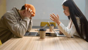 Two coworkers having serious discussion during office meeting, workplace communication and conflict resolution