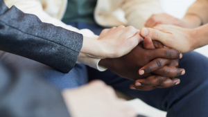 Hands of diverse group holding each other in support, team building and workplace trust concept
