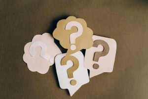 Paper cutout speech bubbles with question marks symbolizing questions and inquiries on a neutral background