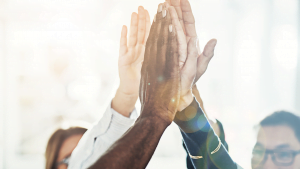 Diverse team giving high-five in celebration with bright sunlight and lens flare effect