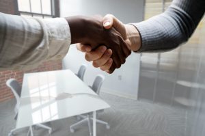 Close-up of two people shaking hands in a modern office conference room