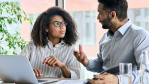 Man and woman discussing work ideas in office with laptop and documents
