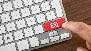 Finger pressing red ESL key on computer keyboard symbolizing English as a Second Language learning