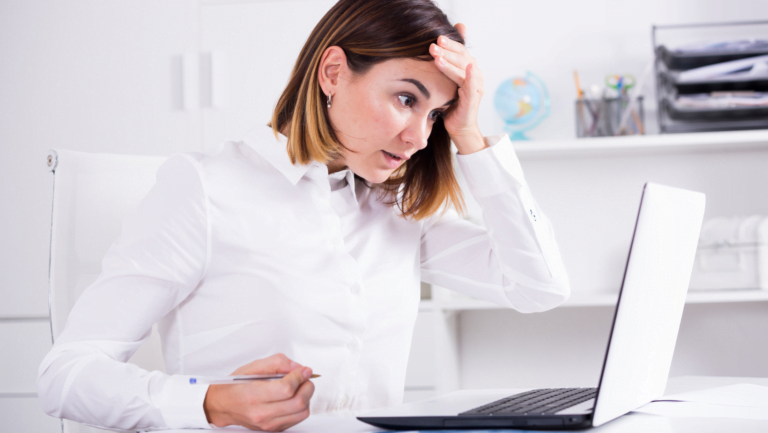 Surprised businesswoman reacting to laptop screen in bright office workspace