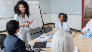 Businesswoman presenting data on flip chart to attentive colleagues in meeting