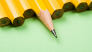 Close-up of sharpened pencil tips lined up on green paper