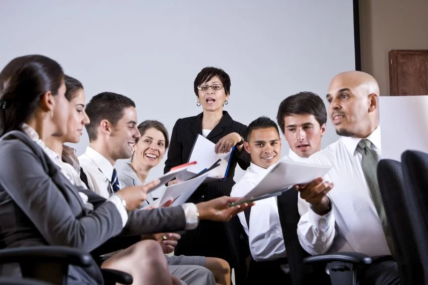 Diverse business team in a meeting room reviewing documents while woman leads presentation