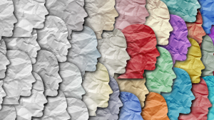 Colorful paper cutout silhouettes of diverse human faces layered together, symbolizing diversity and inclusion
