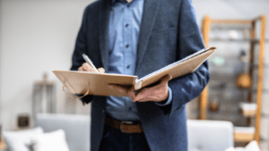 Man in business attire holding a notebook and pen, preparing to take notes or conduct an evaluation