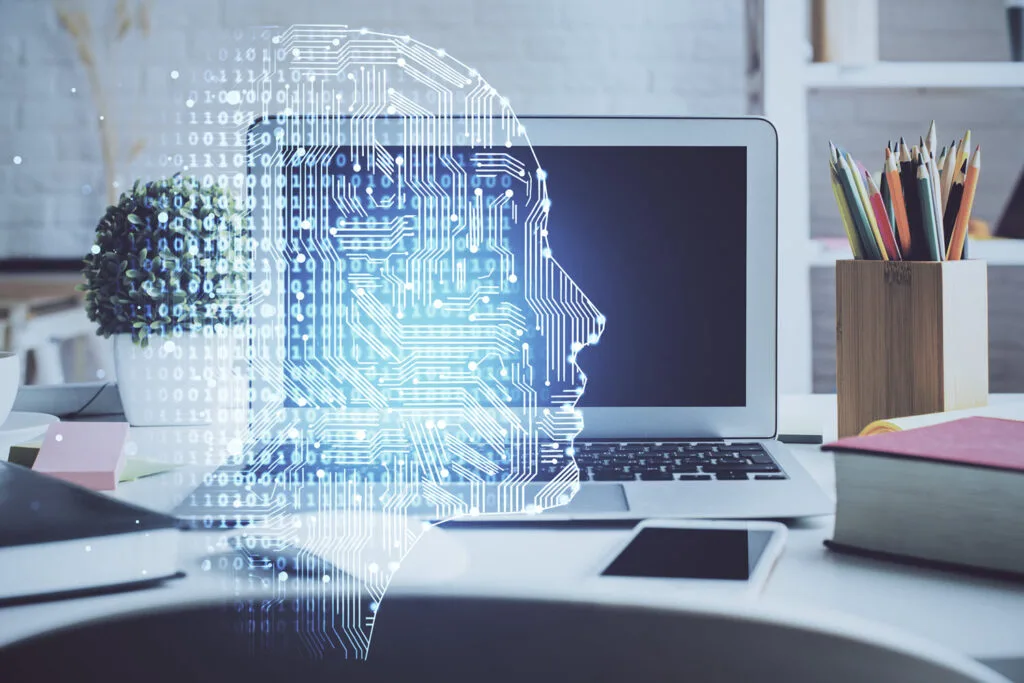 Futuristic digital human face hologram overlay on laptop in modern workspace