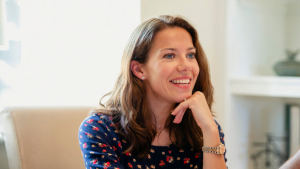 Smiling woman sitting indoors, engaged in conversation or listening attentively, illustrating positive communication or coaching