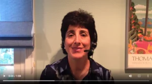 Woman speaking on video wearing headset, sitting in home office with framed art on wall