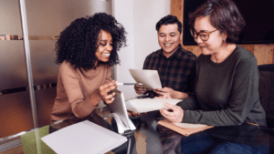 Three diverse professionals collaborating and reviewing documents in a modern office