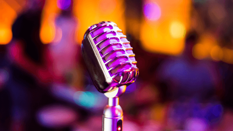 Close-up of vintage microphone with colorful stage lights blurred in background