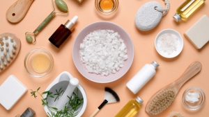 Flat lay of natural skincare and spa products including oils, brushes, and bath salts on a peach background