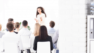 Professional woman presenting charts and business goals on a whiteboard in a well-lit corporate setting