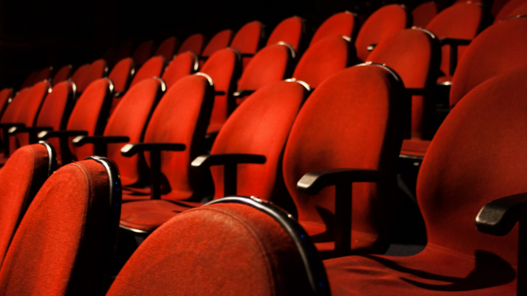 Empty red theater seats arranged in rows, ready for an audience