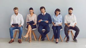 Group of five diverse job candidates sitting in a waiting room preparing for an interview