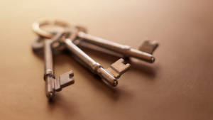 Close-up of three antique brass keys on a wooden table representing the concept of keys to success