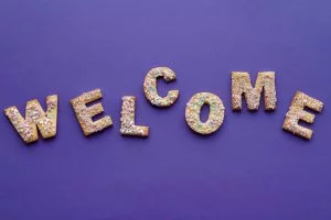 Decorative cookies spelling out the word 'WELCOME' on a purple background