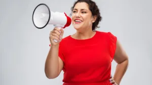 Woman in red dress speaking enthusiastically into a white and red megaphone