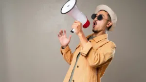 Man using megaphone to make announcement with expressive gesture in casual clothes