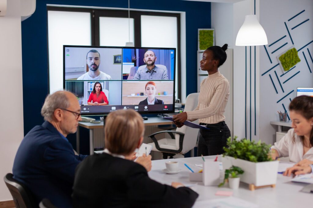 Hybrid meeting room where people at the table and remote participants on a large screen work together