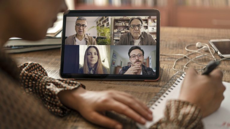 Person taking notes during a virtual video conference call on a tablet device