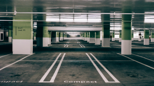 Empty indoor parking garage with marked compact parking spaces and green columns
