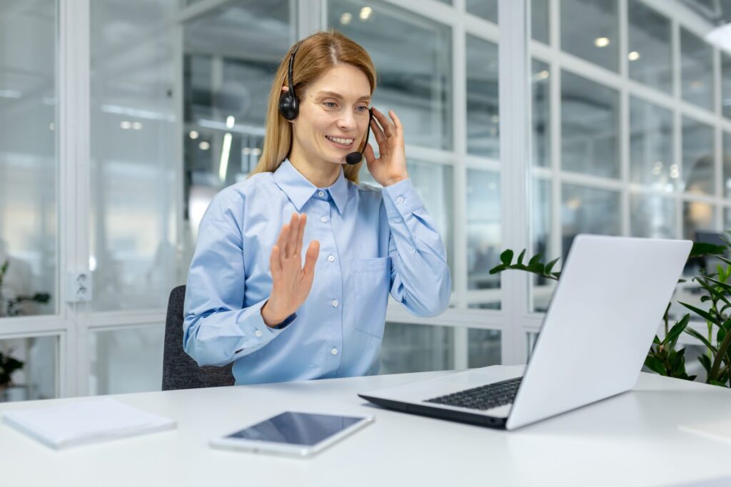 Learner in a headset raises her hand to take part in an online training session