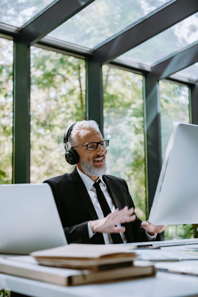 Experienced trainer in headphones leads an online session from a workstation with two screens